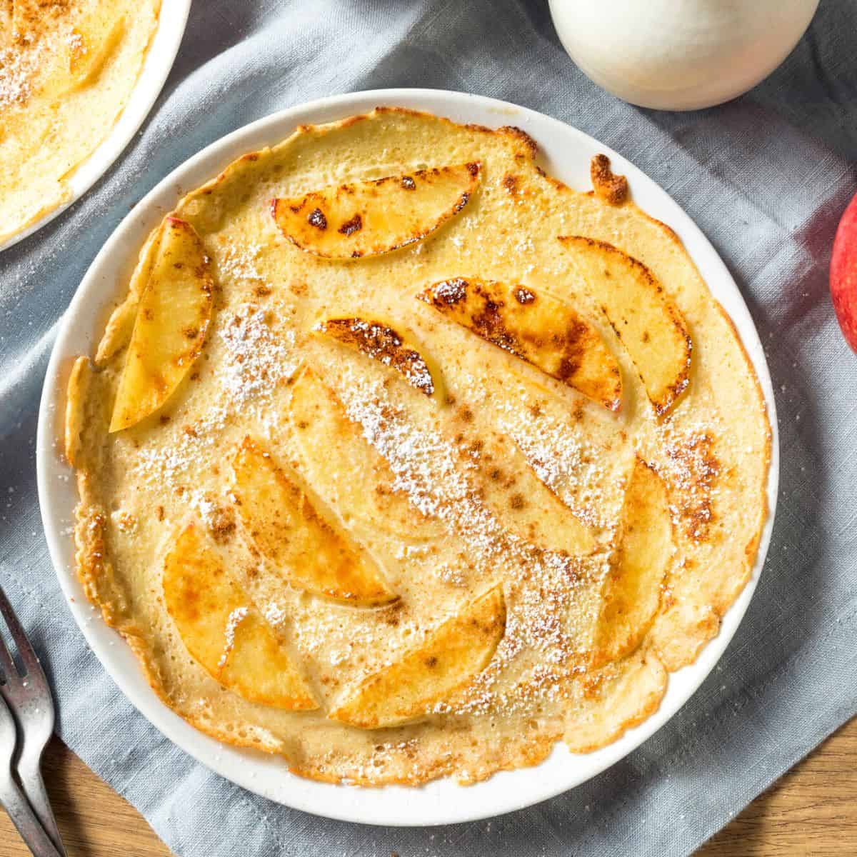 Apple dutch pancakes in a white ceramic dish.