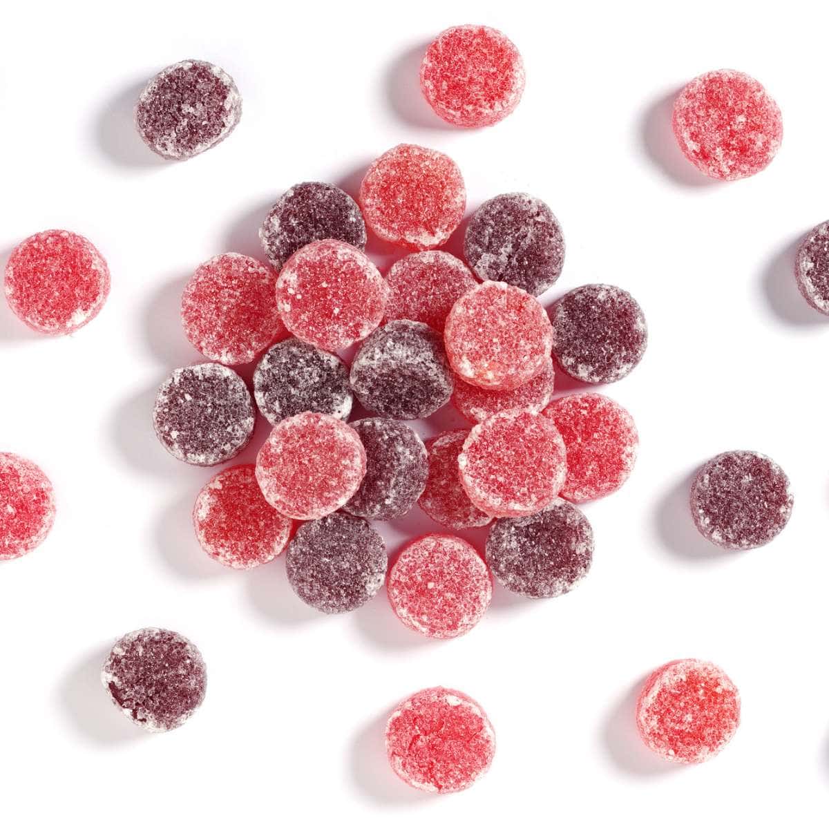 A pile of red and pink British gummy candies on a white surface.