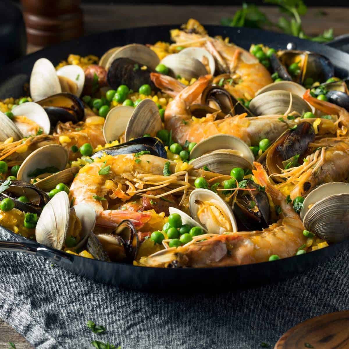 Paella with shrimp and peas in a skillet.