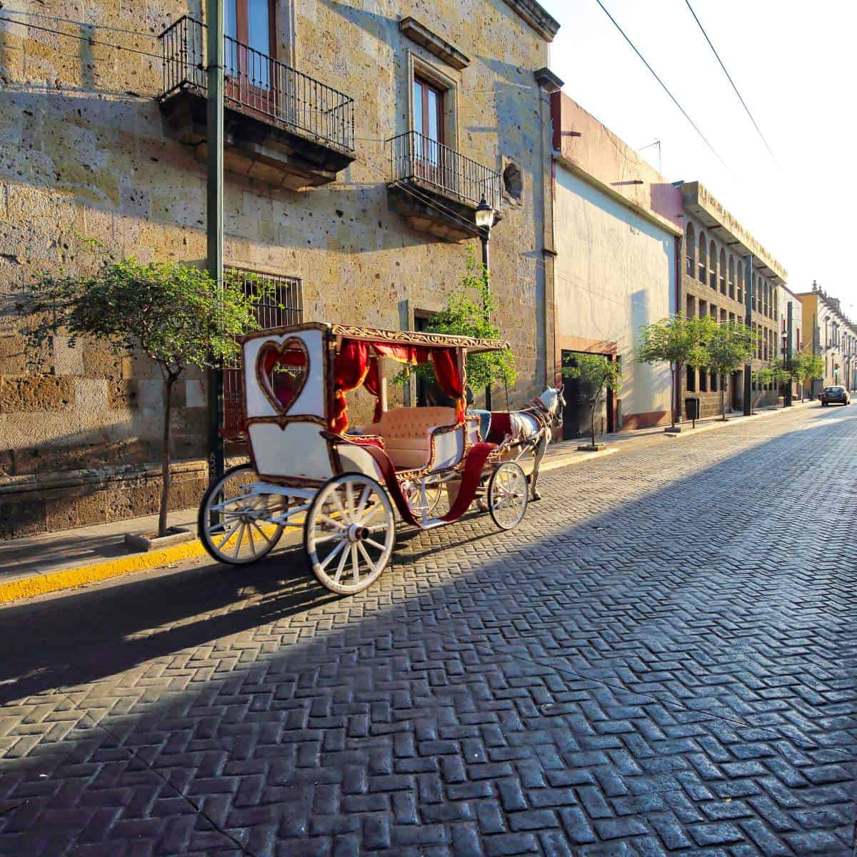 A horse drawn carriage on a cobblestone street.