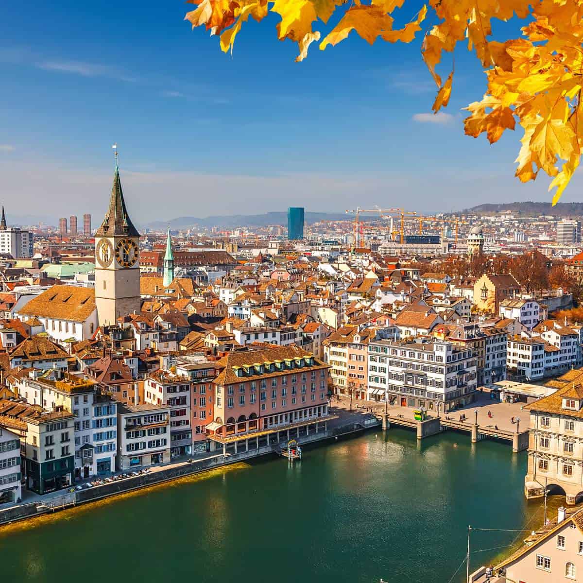 A city in Switzerland known for its picturesque landscapes featuring lush trees and a tranquil river.