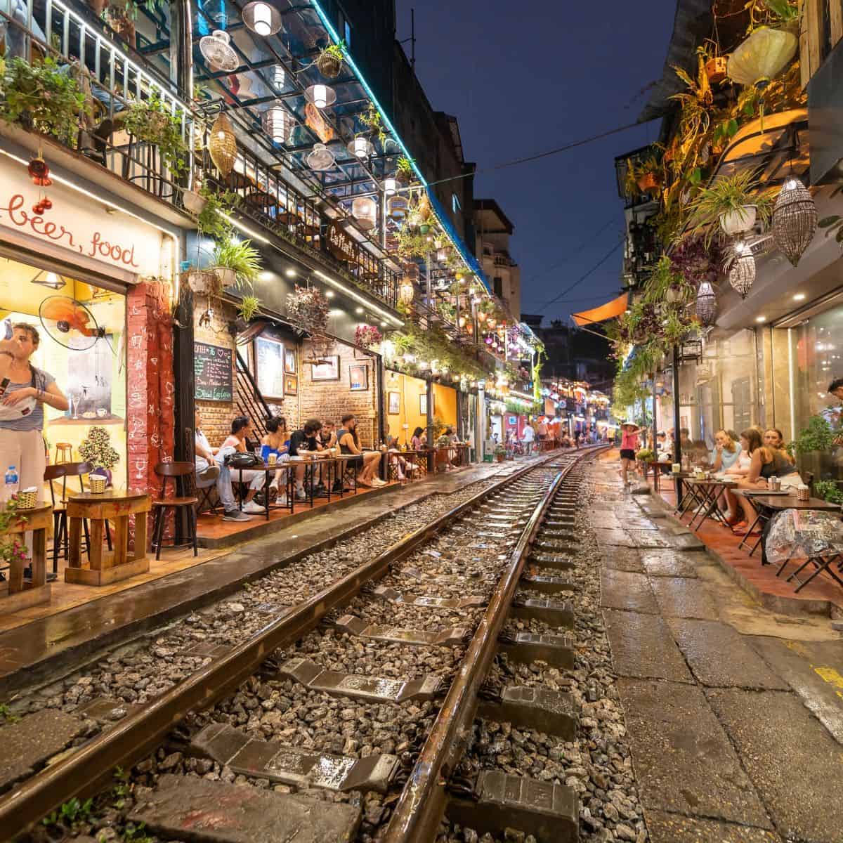 A train track passing through the bustling streets of Hanoi, surrounded by charming cafes.