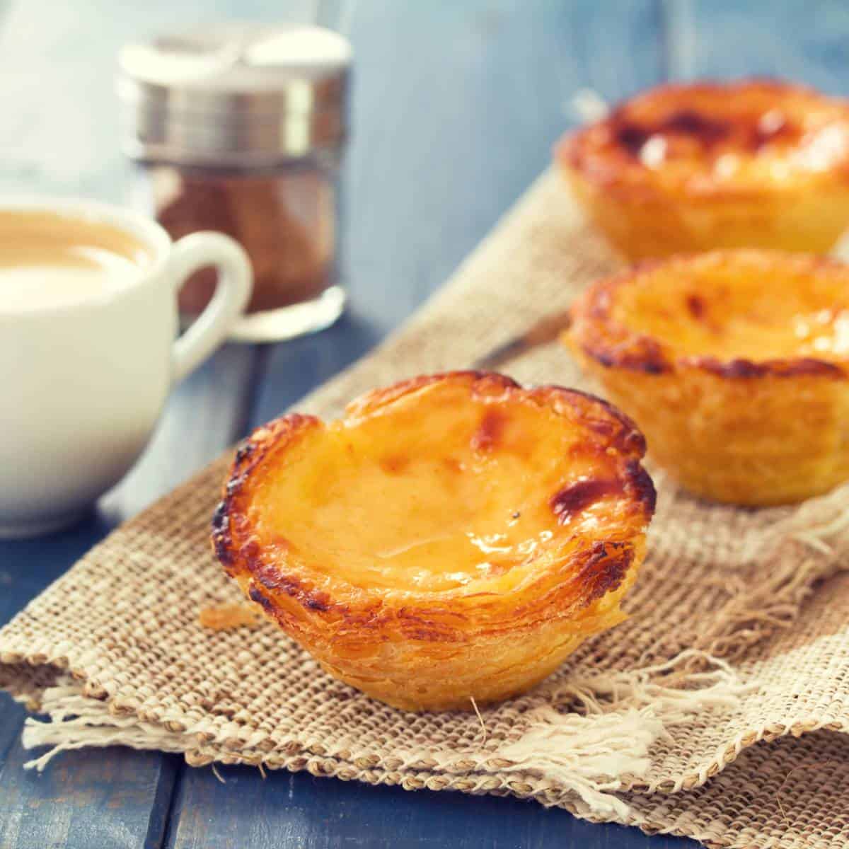 Enjoy a delicious brunch in Lisbon with an assortment of traditional Portuguese pastries displayed beautifully on a rustic wooden table. As you sip on a steaming cup of coffee, immerse yourself in