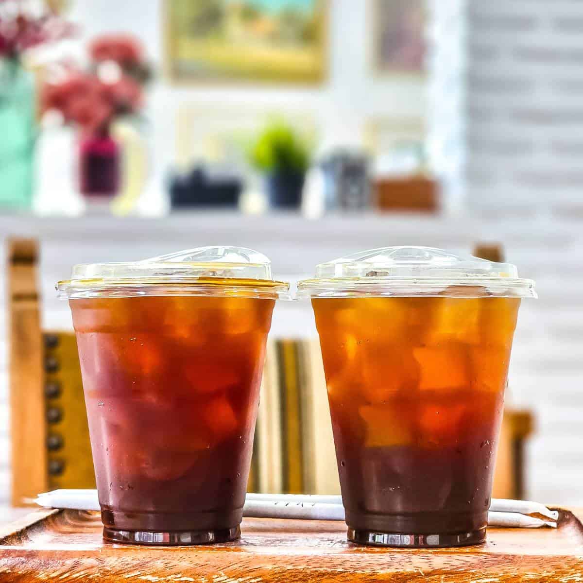Two cups of iced coffee, a popular Filipino drink, sitting on a wooden table.