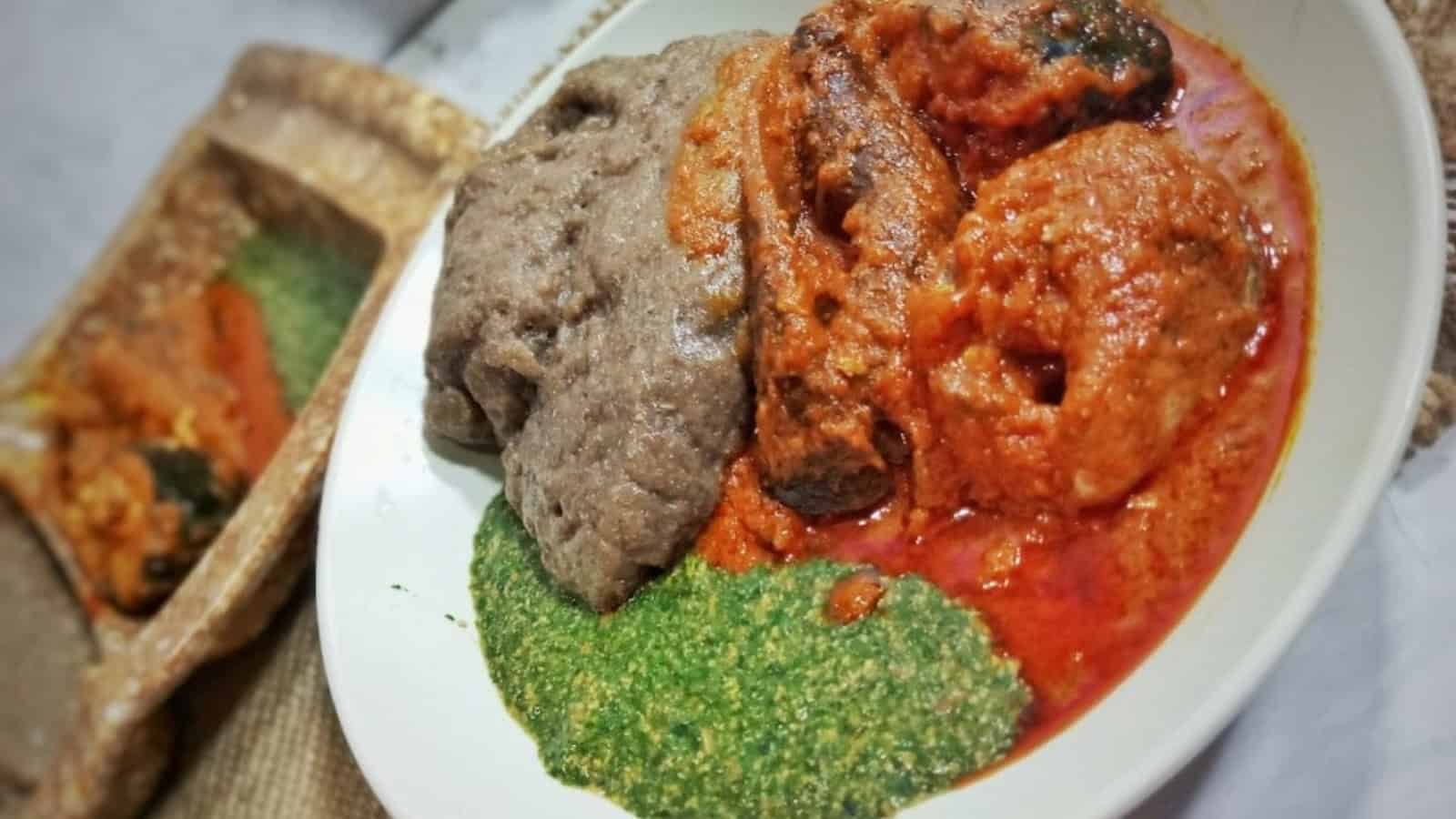 A plate of fufu served with red stew and green spinach sauce.
