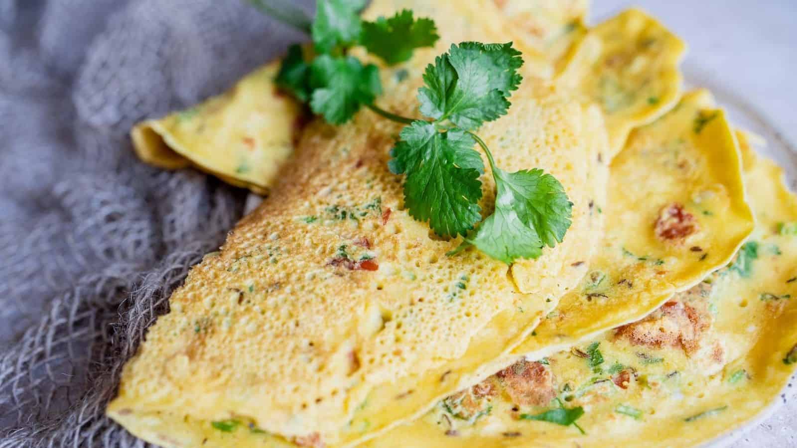 Close-up of savory crepes garnished with cilantro on a textured cloth background.