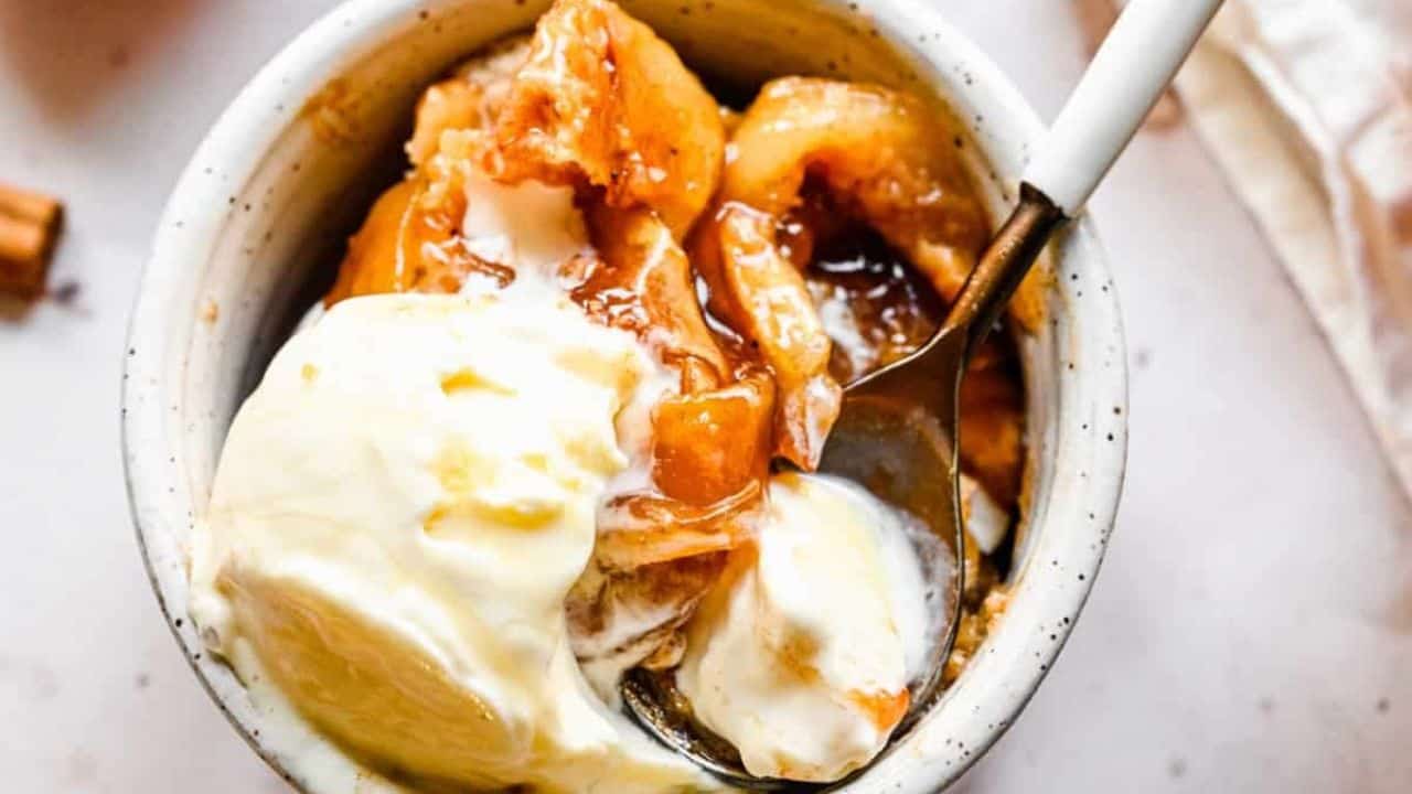 An overhead image of bisquick apple cobbler in a skillet pan topped with vanilla ice cream.