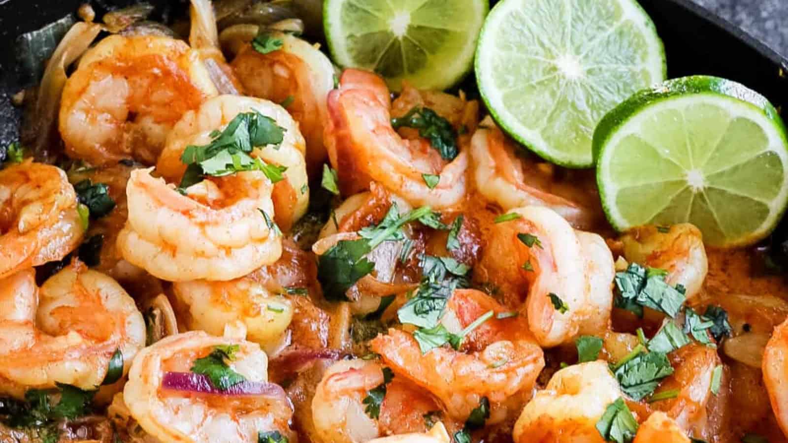 Shrimp stuffed into soft corn tortillas with lime wedges on the side.
