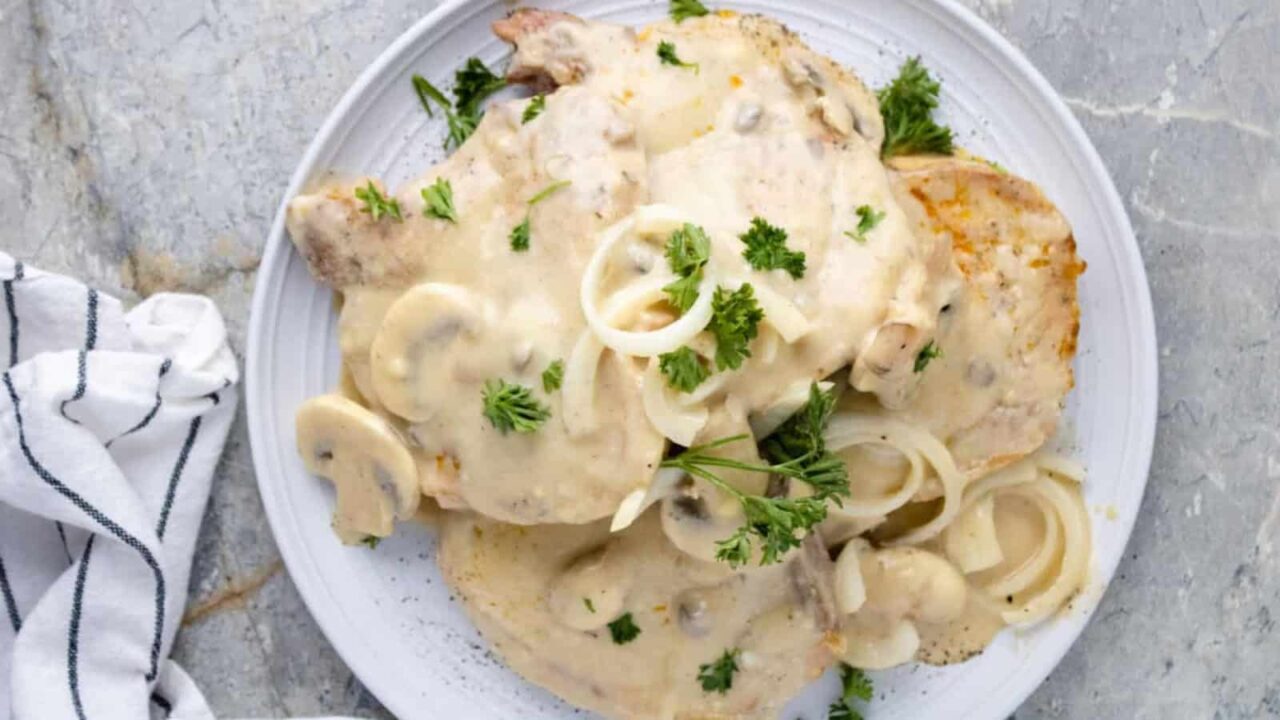 Slow Cooker Pork Chops on a plate covered with a creamy mushroom gravy and served on mashed potatoes.