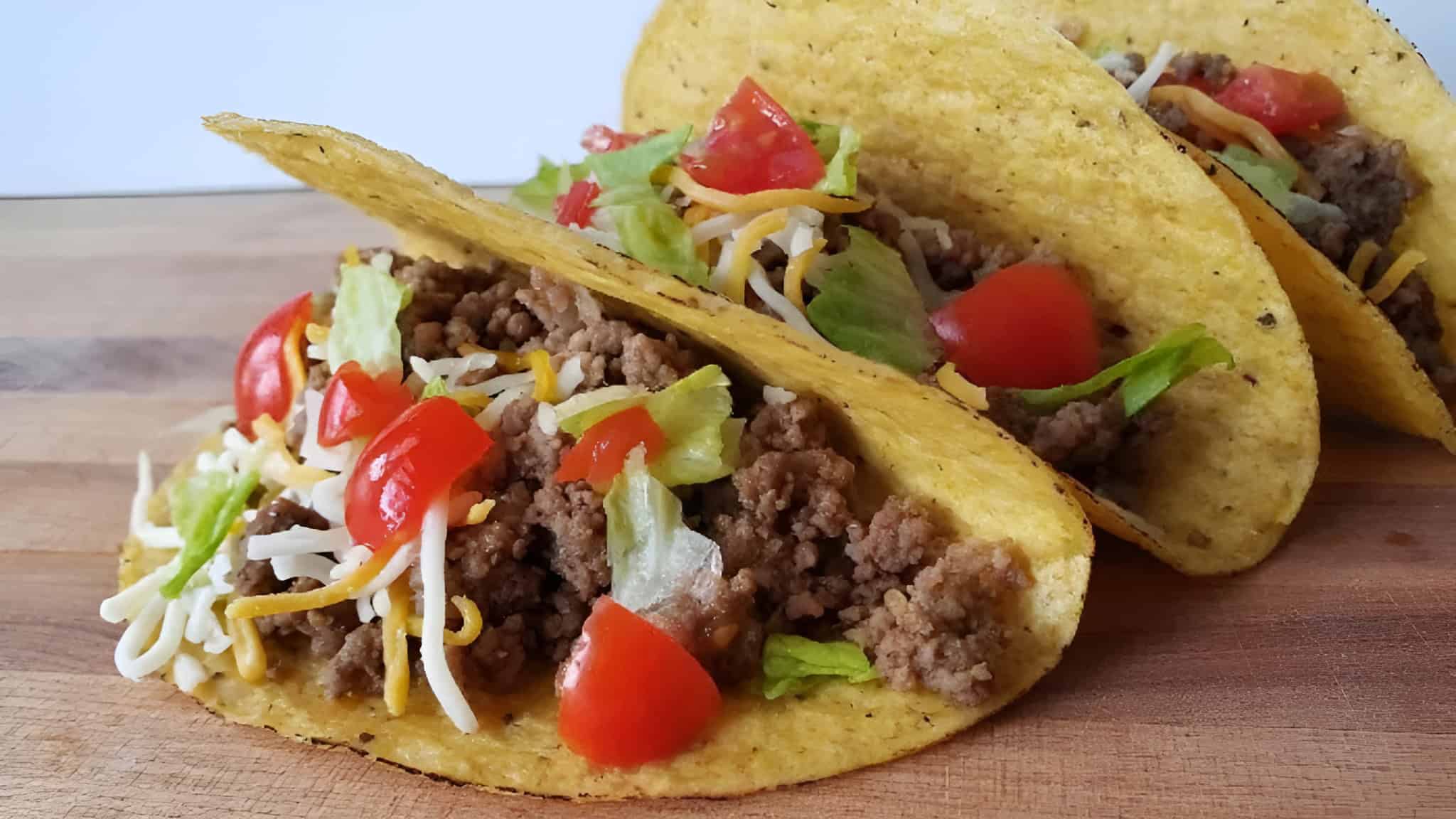 Image shows three honey habanero tacos with corn shells sitting on a wooden board.