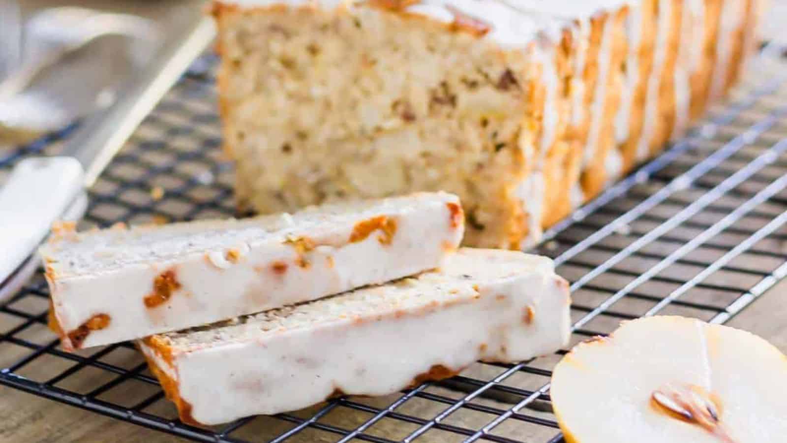 Sliced loaf of nut bread with icing, placed on a cooling rack.