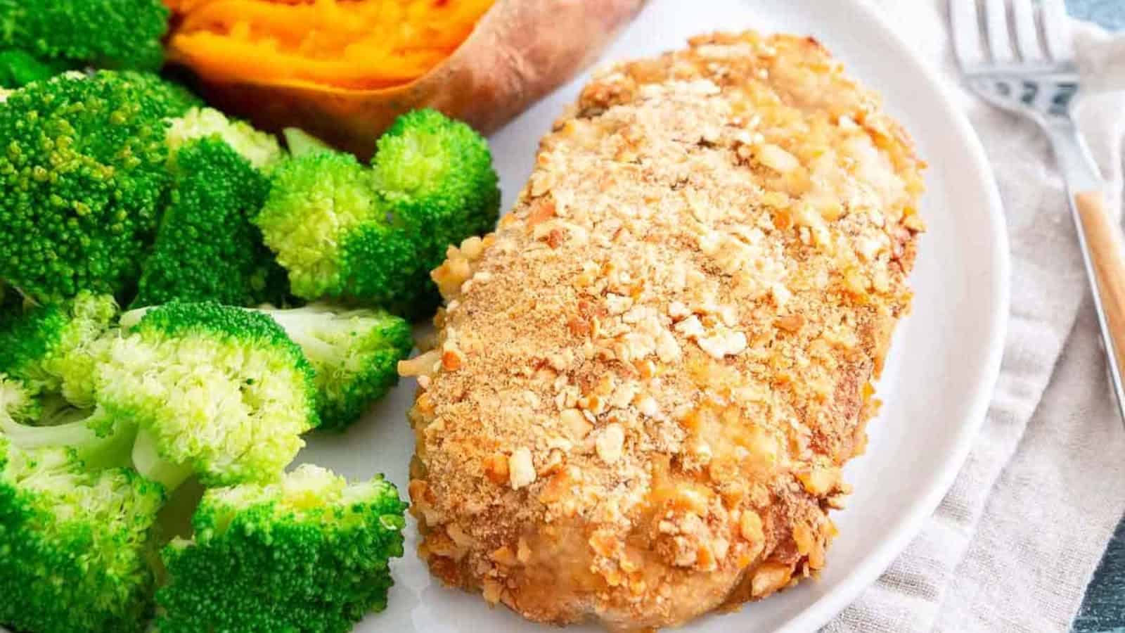 A plate with baked chicken breast, broccoli, and a halved sweet potato.