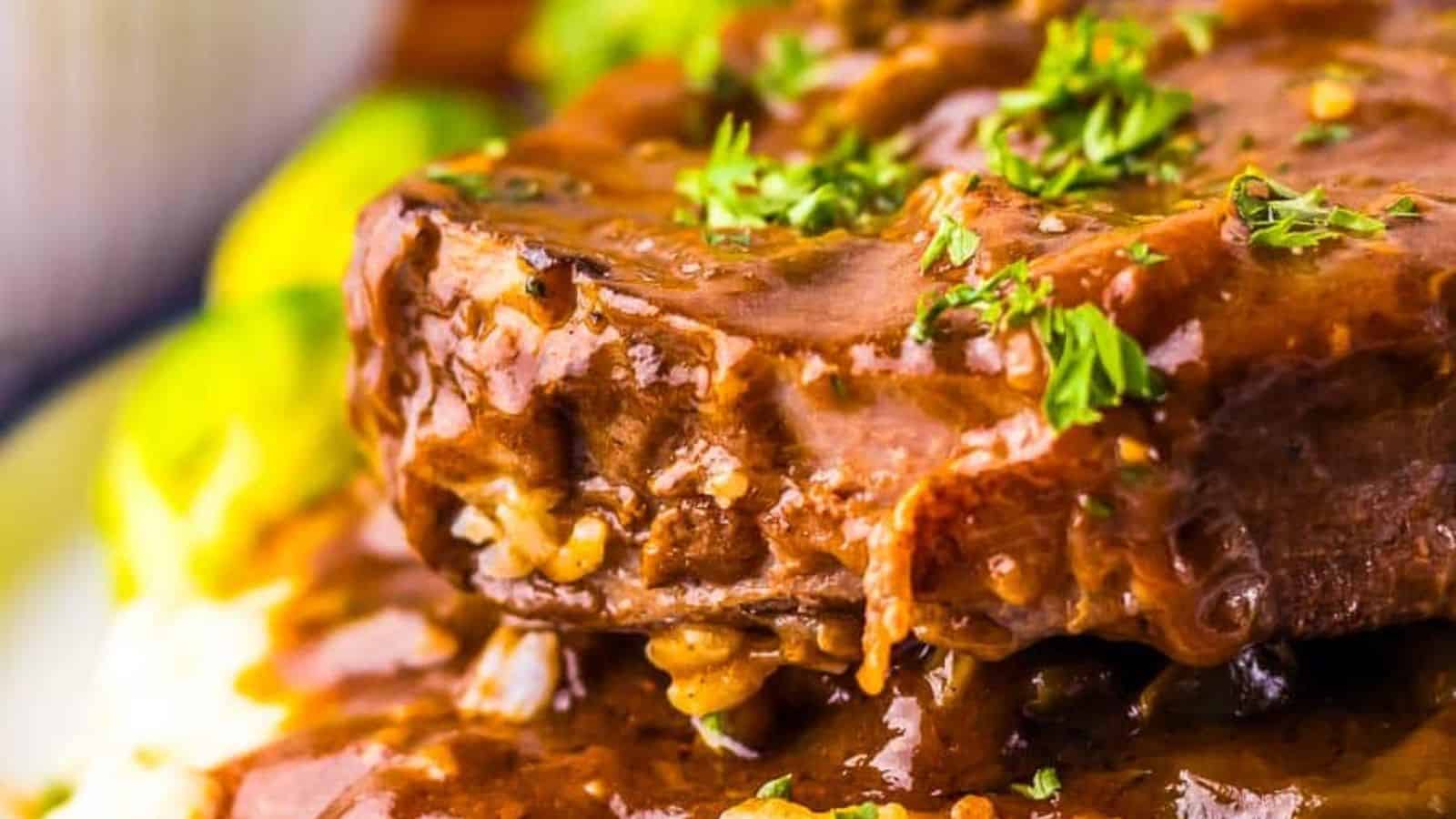 Close-up of a savory beef steak topped with gravy and garnished with chopped parsley, served with a side of mashed potatoes and vegetables.