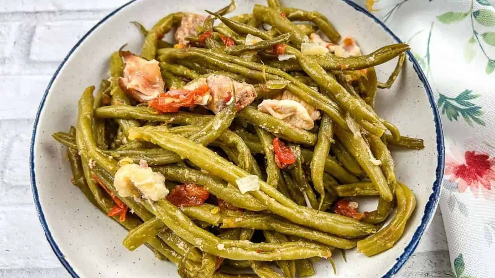 Green beans with sausage on a white plate.