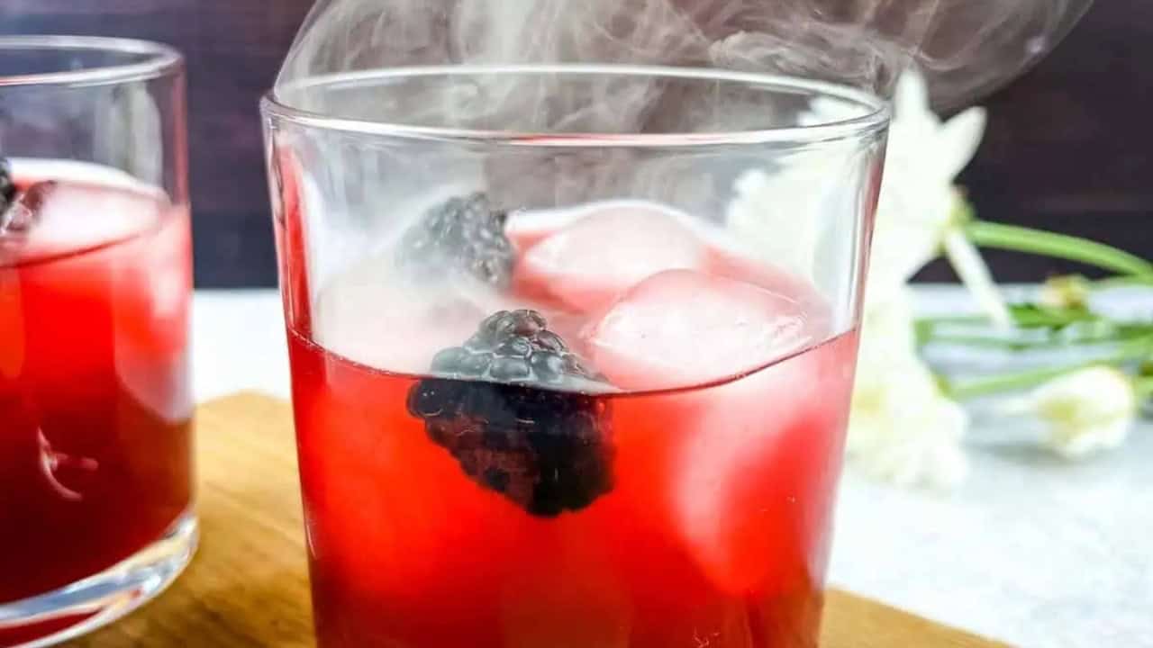 Smoked Blackberry Margarita with smoke coming out the top of the glass.