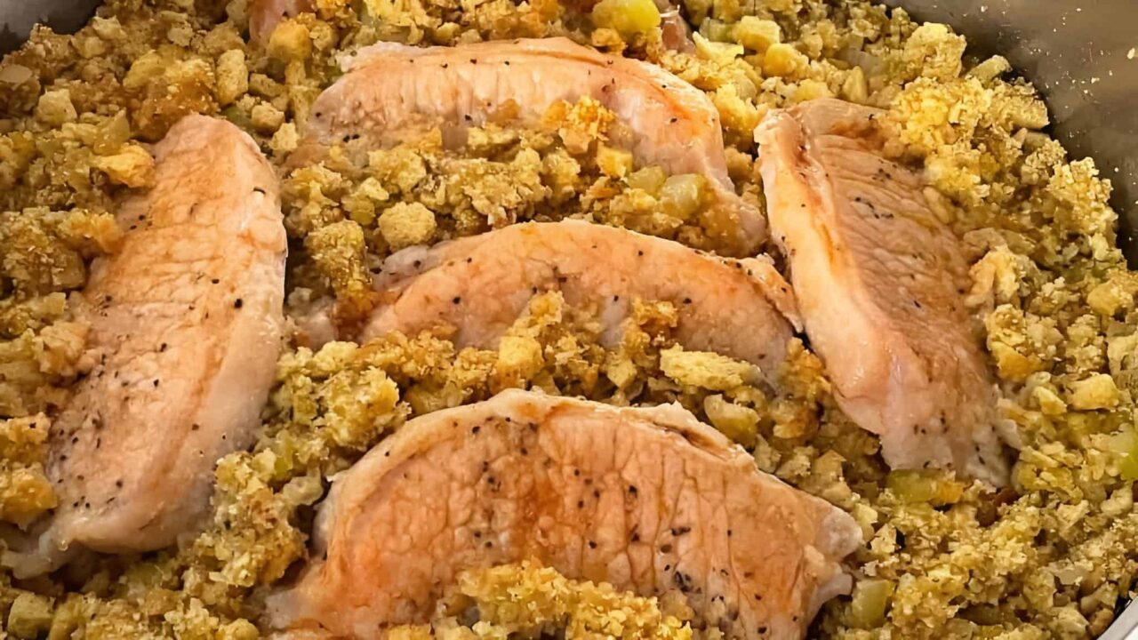 Five cooked salmon fillets surrounded by seasoned stuffing mix with diced vegetables.