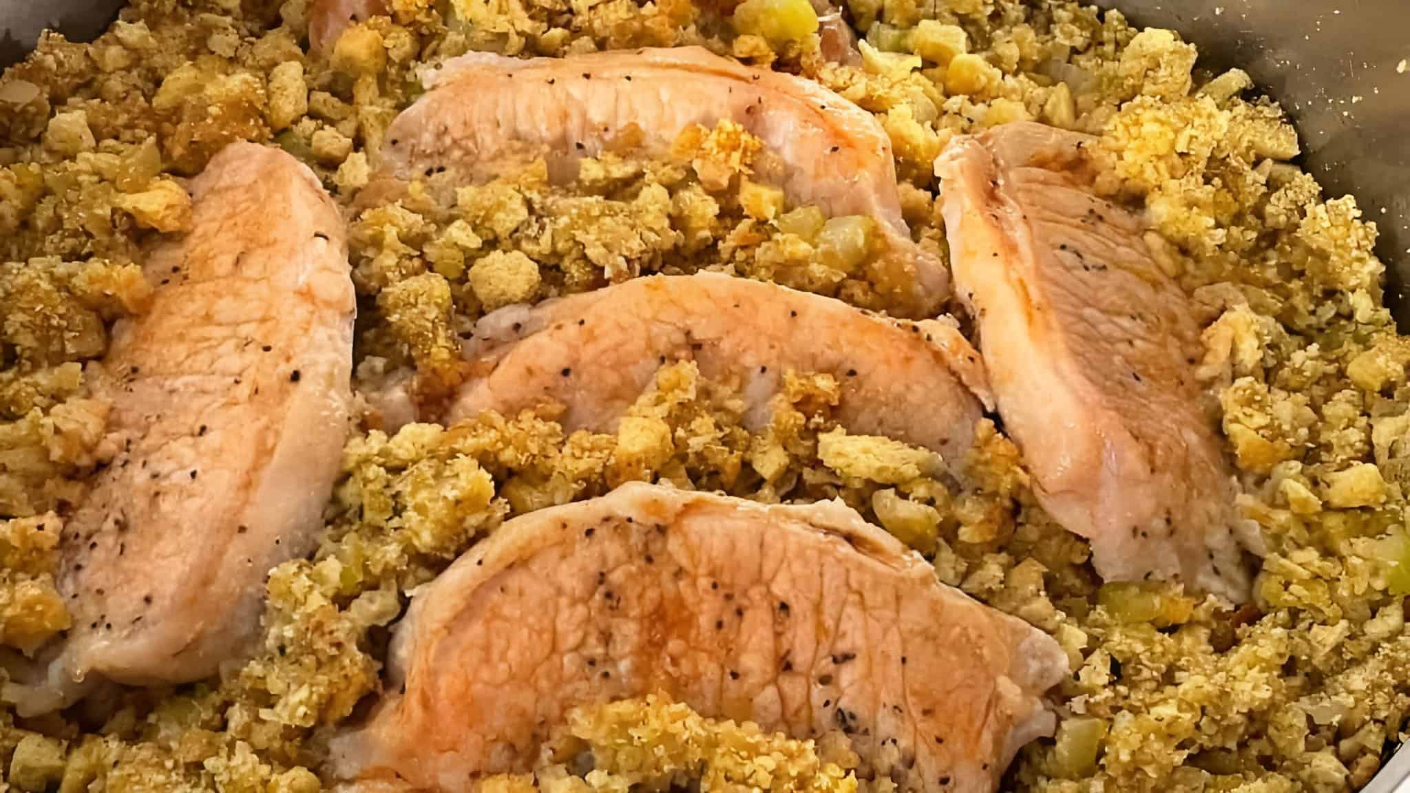 Five cooked salmon fillets surrounded by seasoned stuffing mix with diced vegetables.