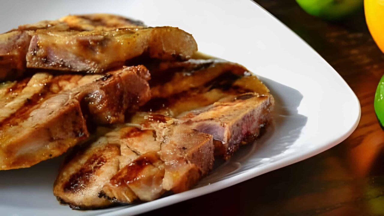 Grilled pork chops stacked on a white plate.