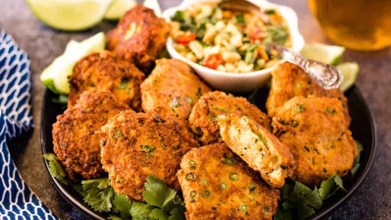 Thai fish cakes on a black plate with prik nam pla.
