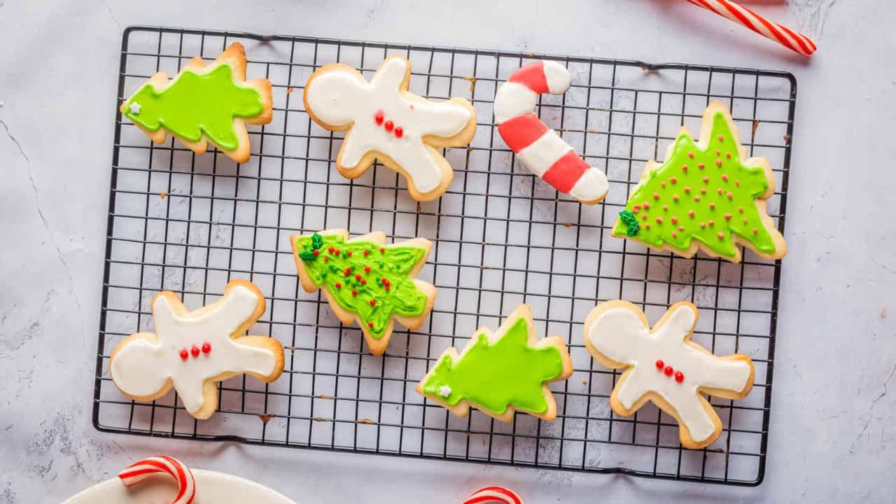 Overhead view of Christmas sugar cookies on a white plate, with cookies on the side as well.