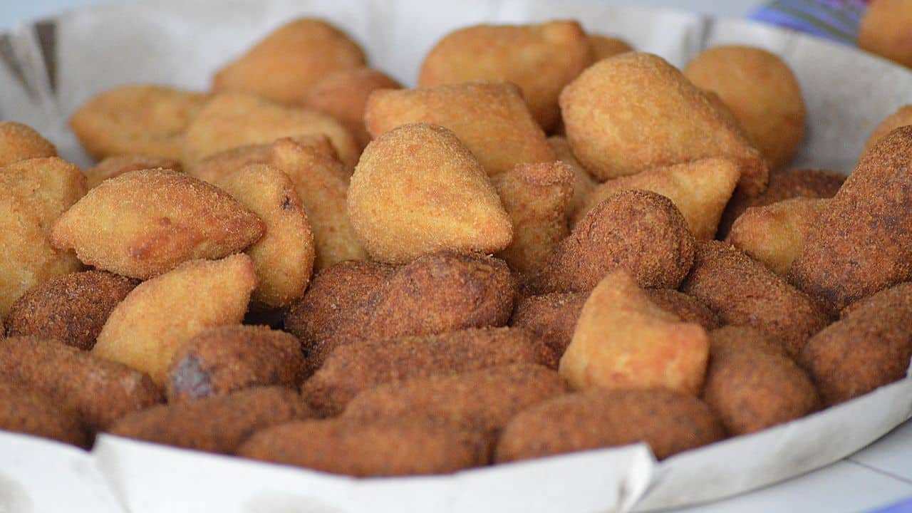 An assortment of fried pastries stacked on a white paper lining.