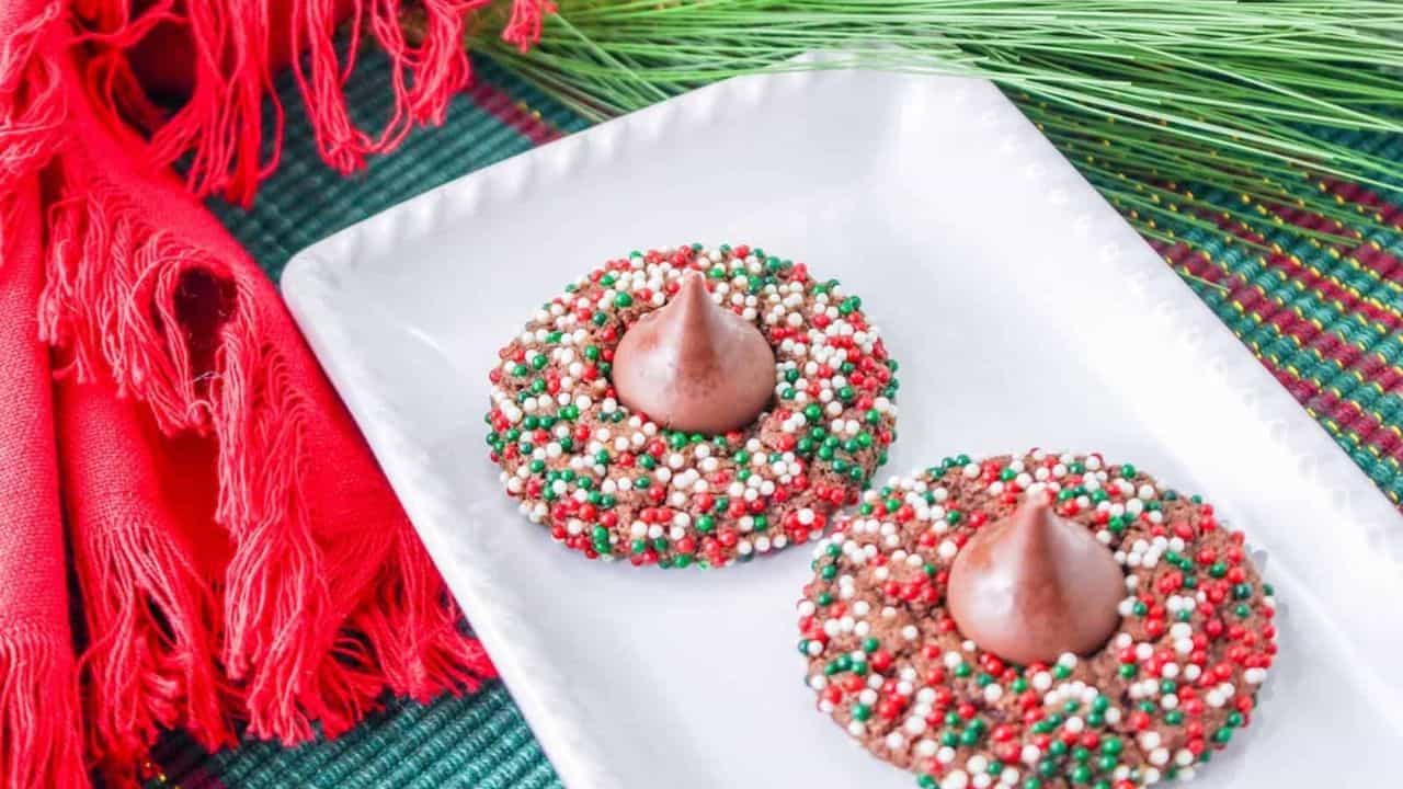 Two chocolate blossom Christmas cookies on a white plate.