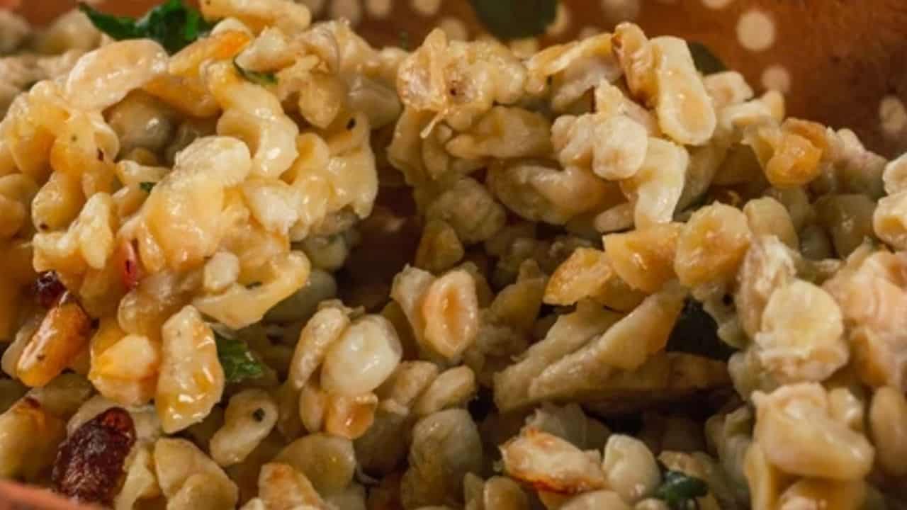Close-up of a dish featuring cooked corn kernels with herbs and a creamy sauce, served in a polka dot bowl.