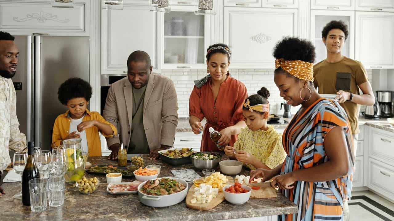 A group of people preparing and serving a variety of dishes in a bright kitchen setting.