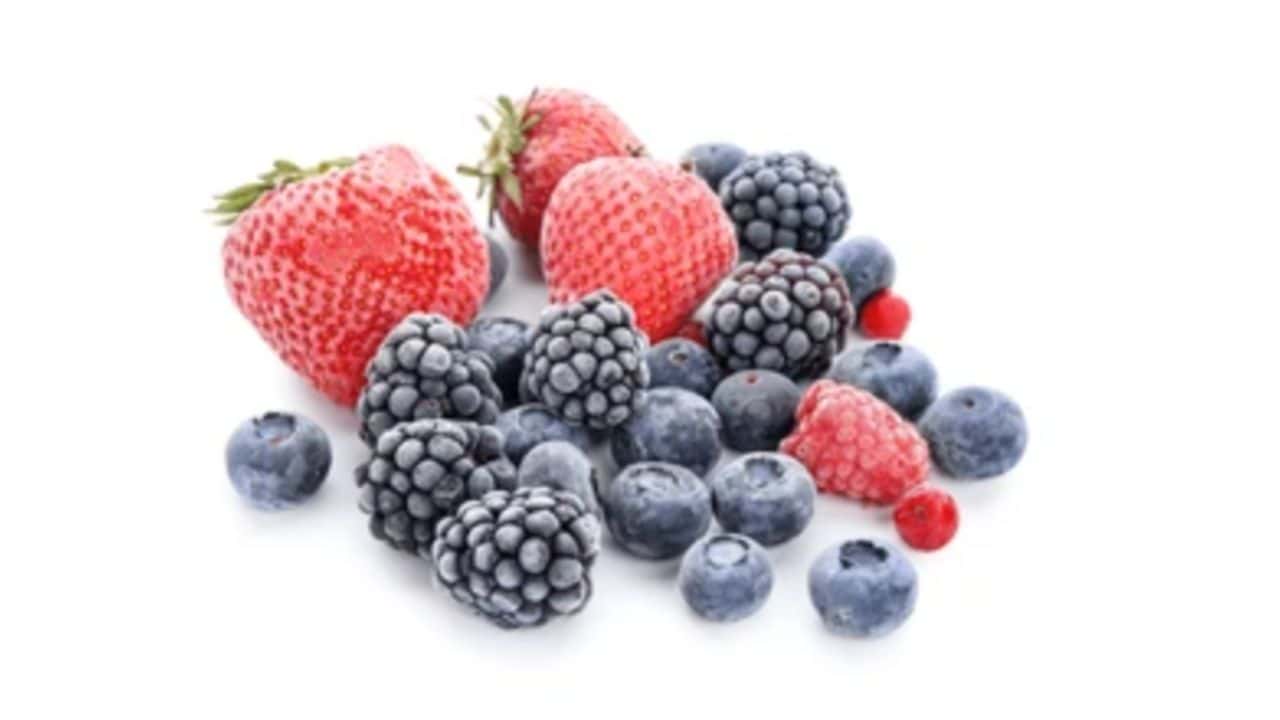 A variety of mixed berries including strawberries, blueberries, blackberries, and raspberries on a white background.