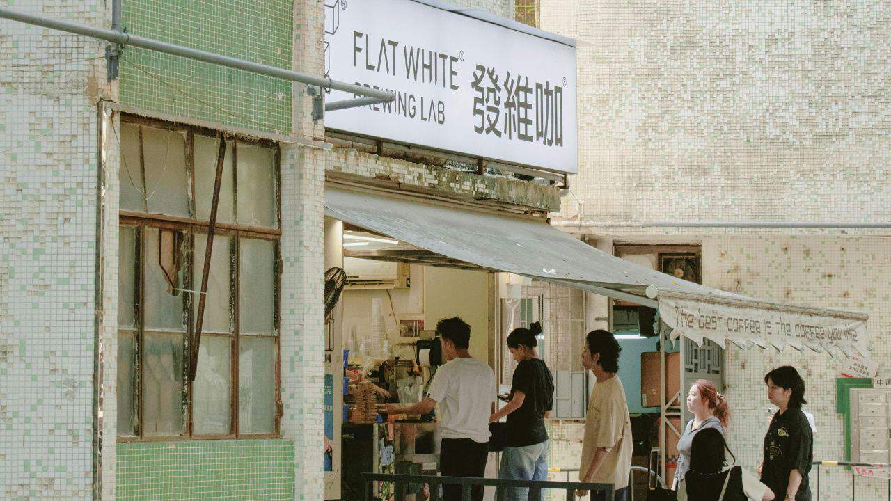 People standing at a counter inside a small shop called "Flat White.