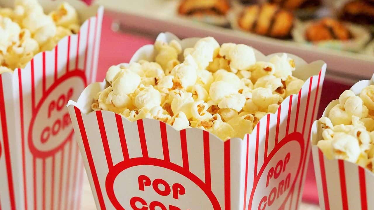 Boxes of popcorn with red-striped design are displayed, filled to the top with popped kernels.