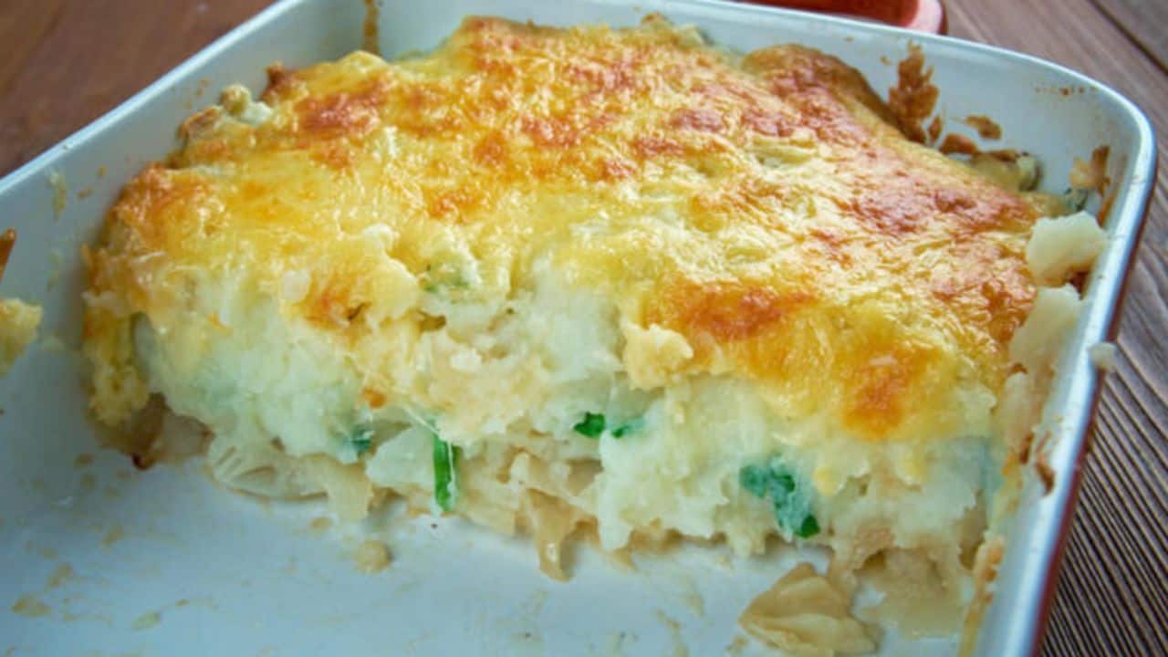 A half-eaten casserole dish with a golden, cheesy top and layers of potatoes and vegetables.