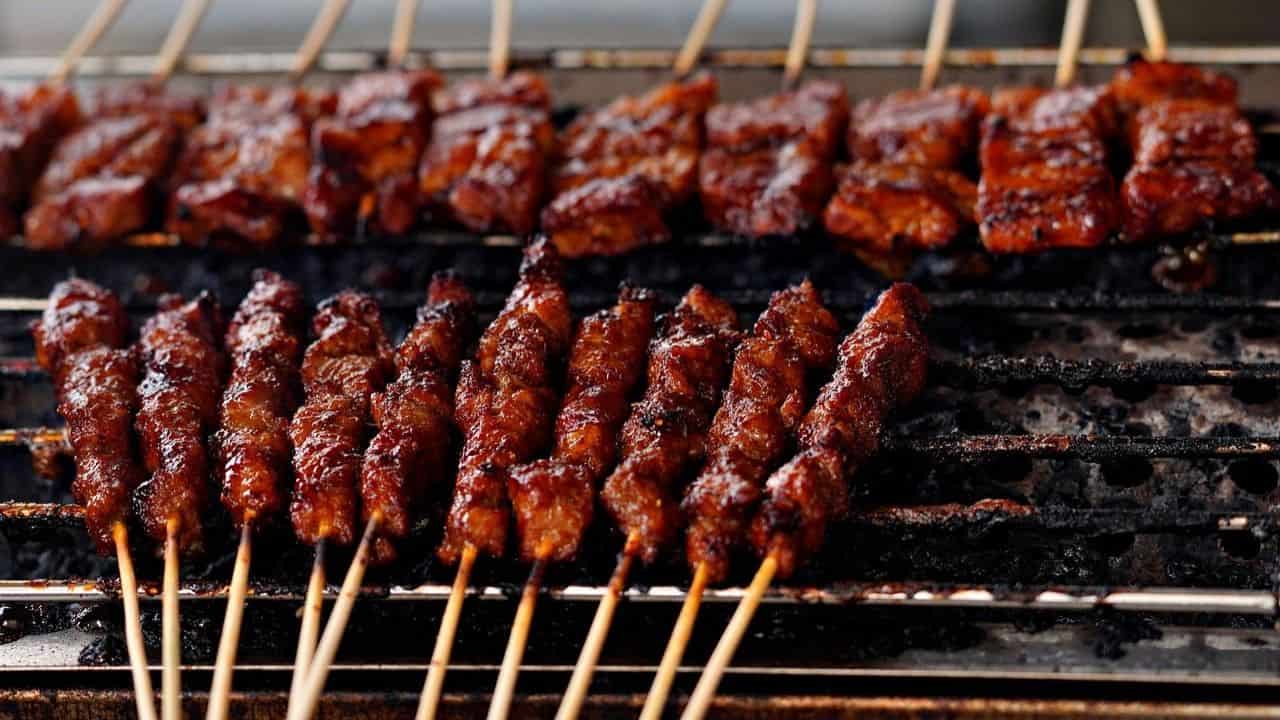 Skewers of marinated meat grilling on a barbecue.