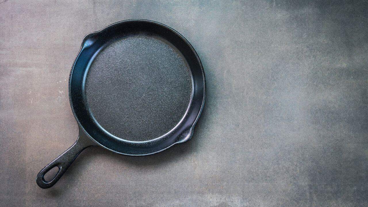 A black cast iron skillet rests on a gray surface.