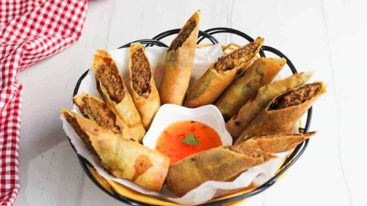 Filipino spring rolls in a basket with dipping sauce.
