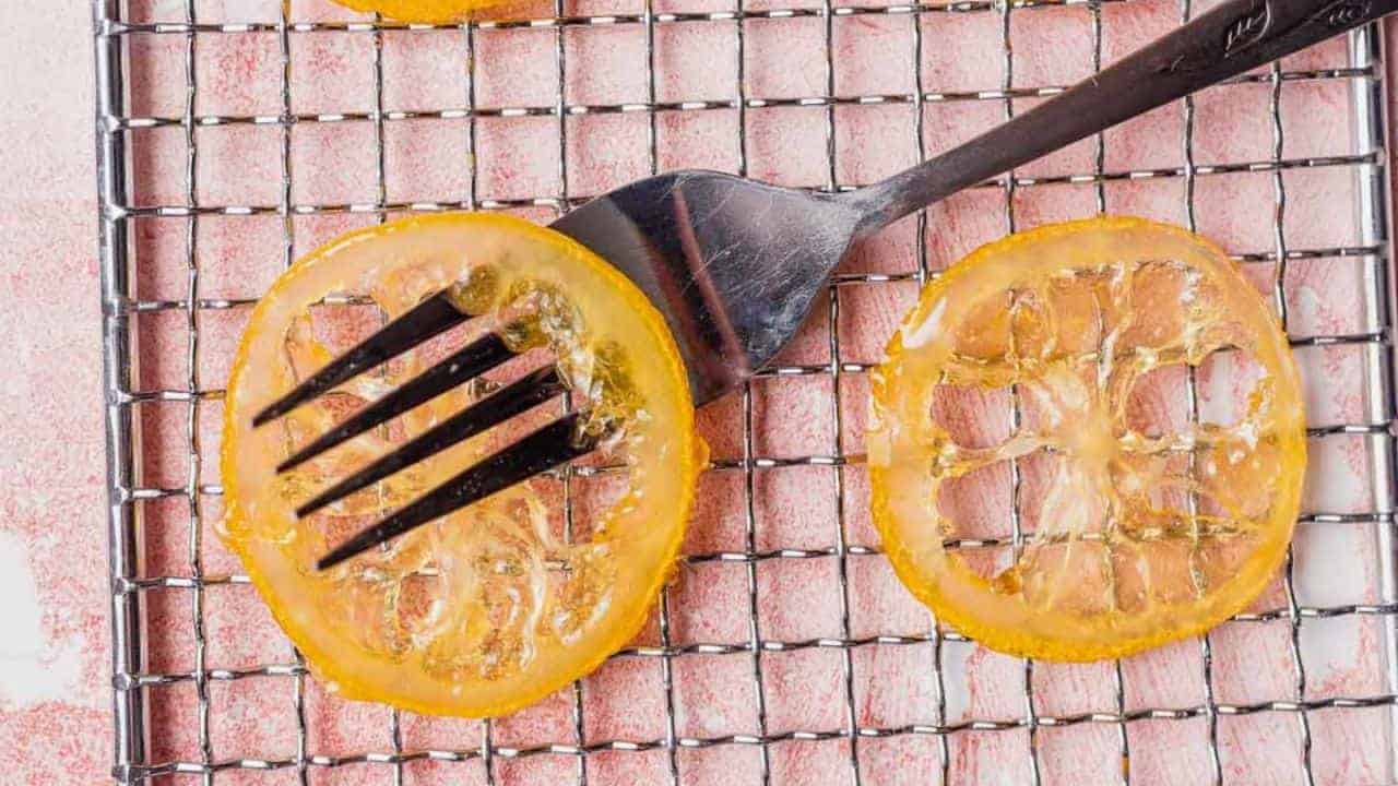 Slices of candied citrus on a cooling rack with a fork resting on one slice.