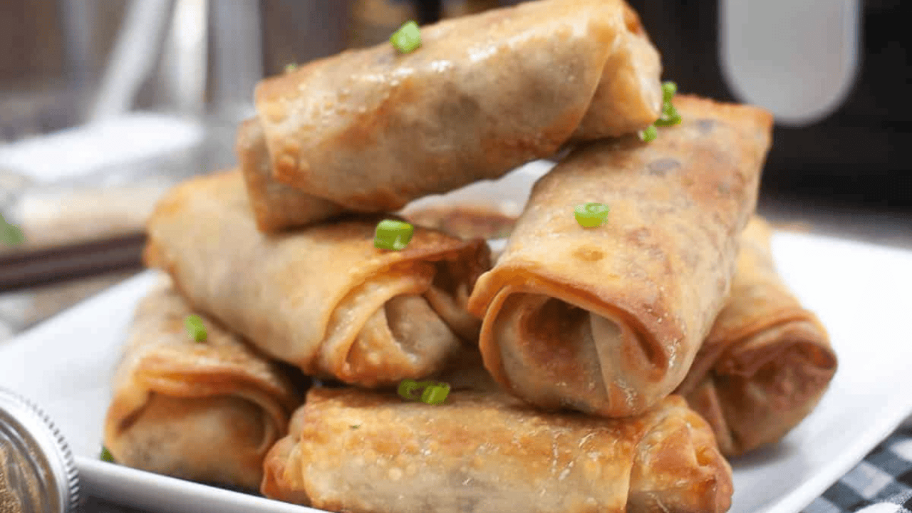 Stacked spring rolls on a white plate.