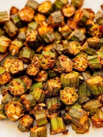 A plate of sliced, cooked okra with a wooden spoon.