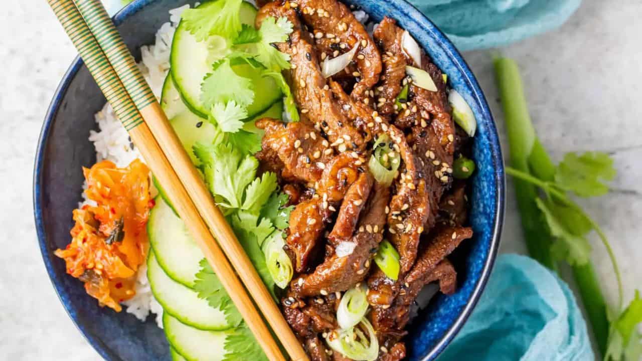 Beef bulgogi in a bowl with rice and cucumbers.