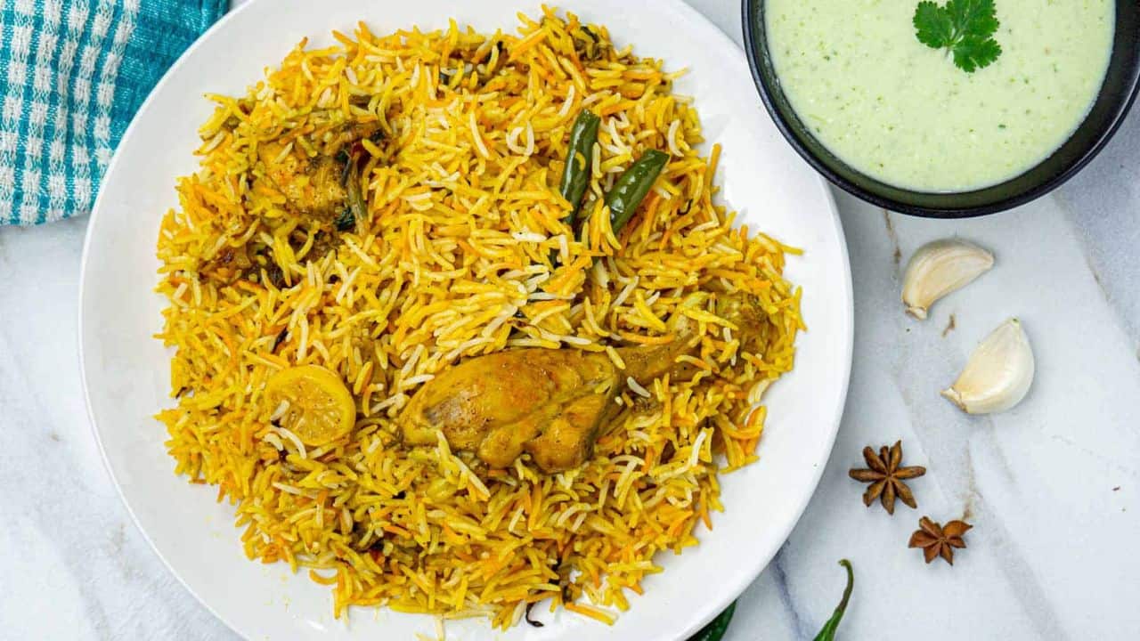 Chicken biryani on a plate with raita.