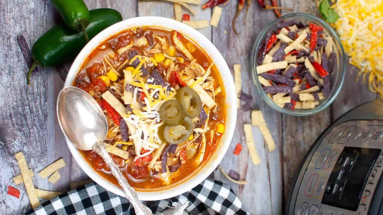 Low angle shot of a white bowl filled with tortilla soup. There is an instant pot in the background.