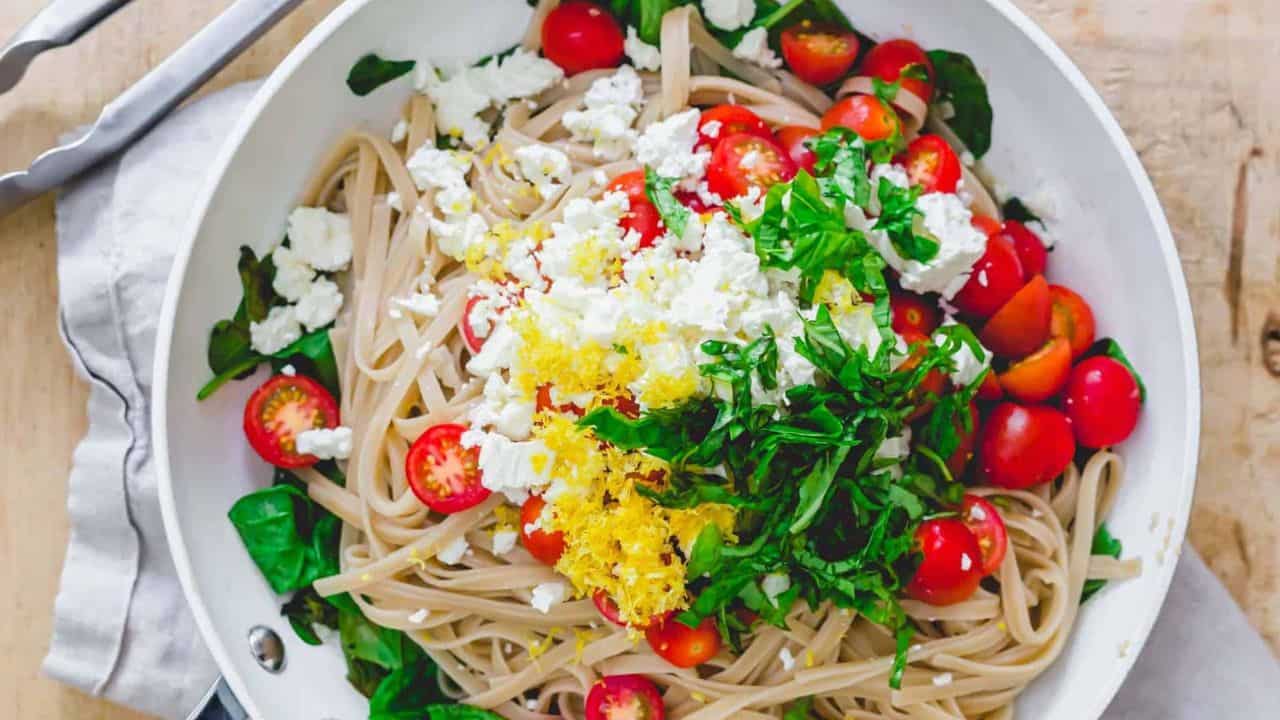 Lemon pasta with spinach, feta and cherry tomatoes in a bowl.