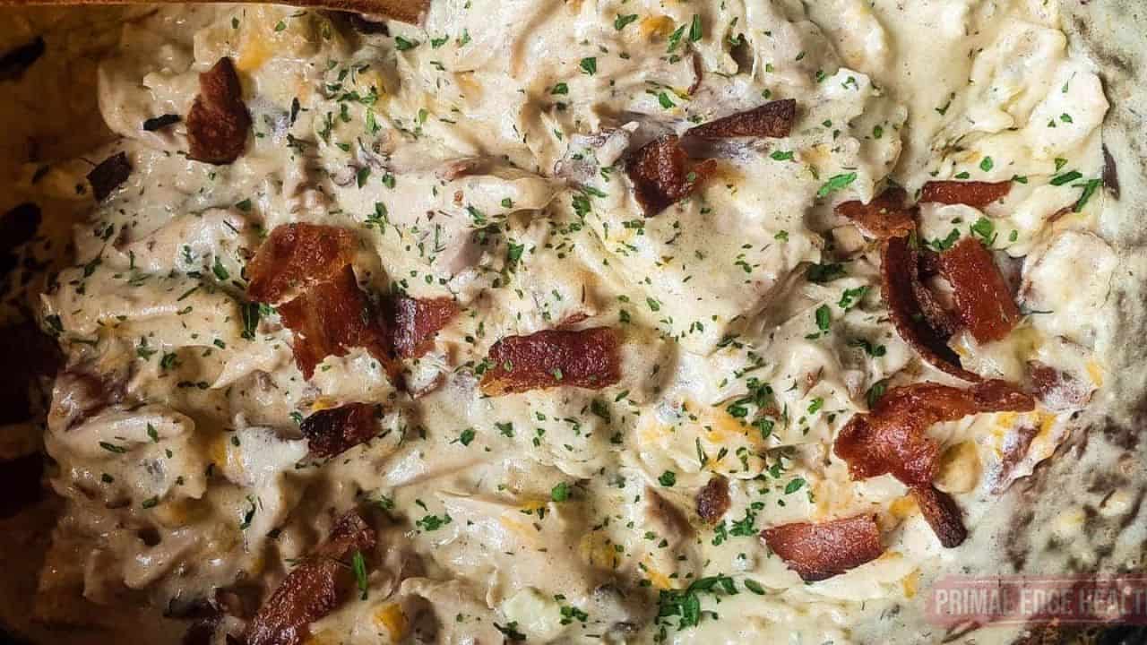 A picutre of cheesy chicken with bacon and dried parsley.