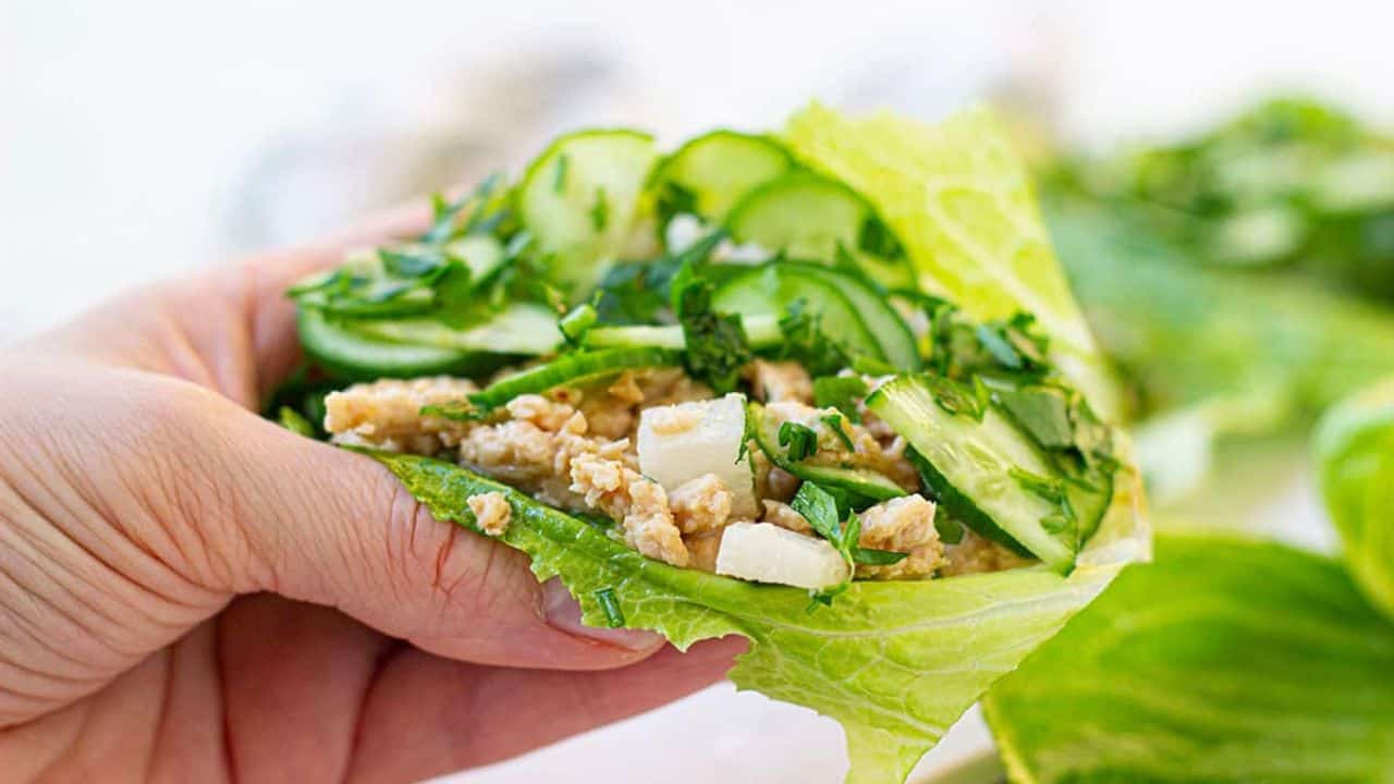 Thai chicken lettuce wraps with peanut sauce on a white plate.
