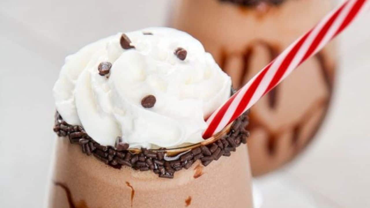 A mudslide drink topped with whipped cream, chocolate chips, and sprinkles.