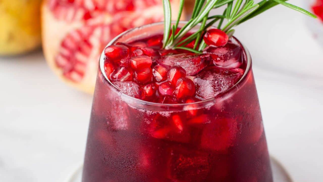A refreshing cocktail made with pomegranate juice and garnished with rosemary sprigs.