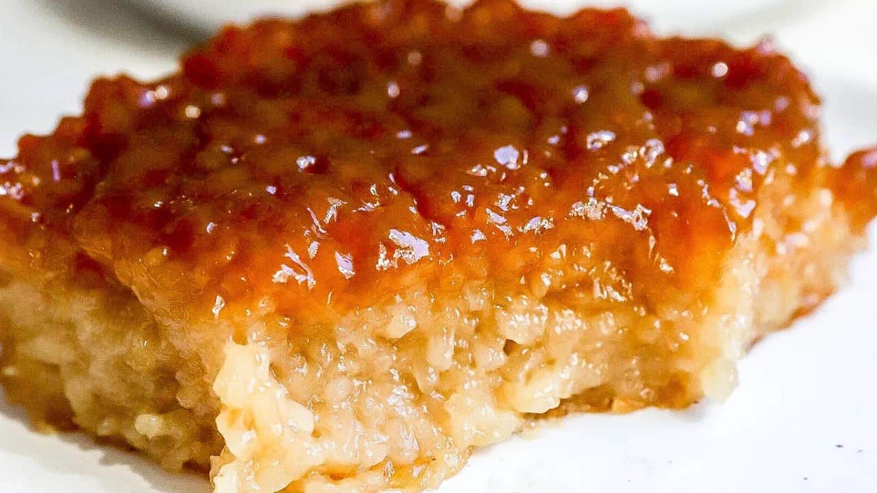 A piece of sticky rice dessert with a shiny caramelized topping placed on a white surface.