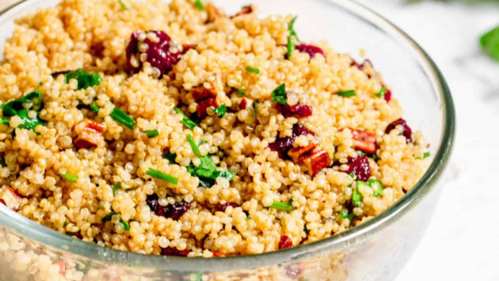 A glass bowl filled with quinoa, dried cranberries, and pecans.