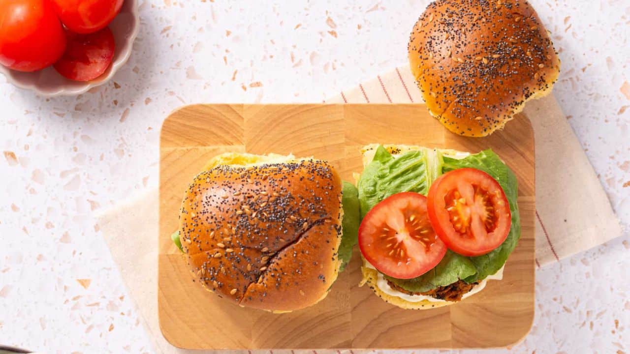 An image of black bean quinoa burger on a cutting board with the top bun on the side.