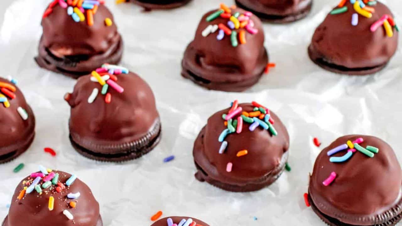 Chocolate covered ice cream bites on a piece of parchment paper.